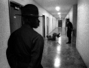 In a hallway a drill instructor watches as a young boot gives another DI 25 sit ups.